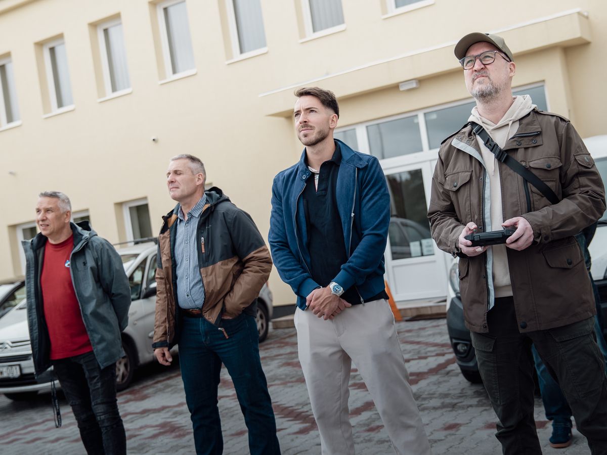 Négy résztvevő figyeli a levegőben lévő drónt egy szabadtéri gyakorlaton