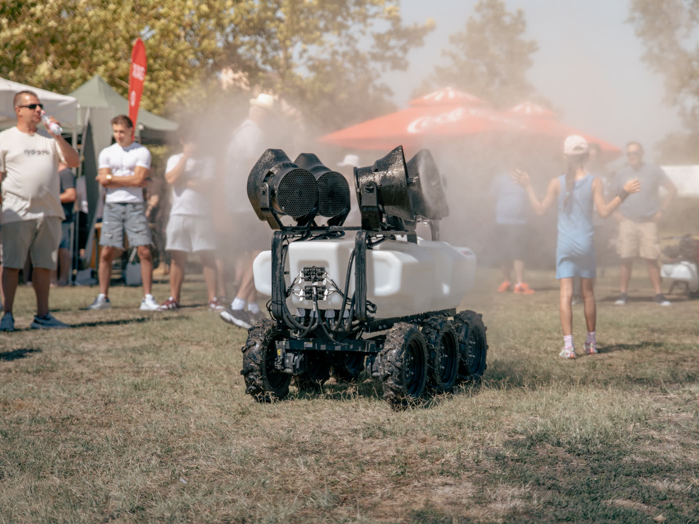 Önjáró permetező robot bemutatója füstfelhőben, körülötte a nézők
