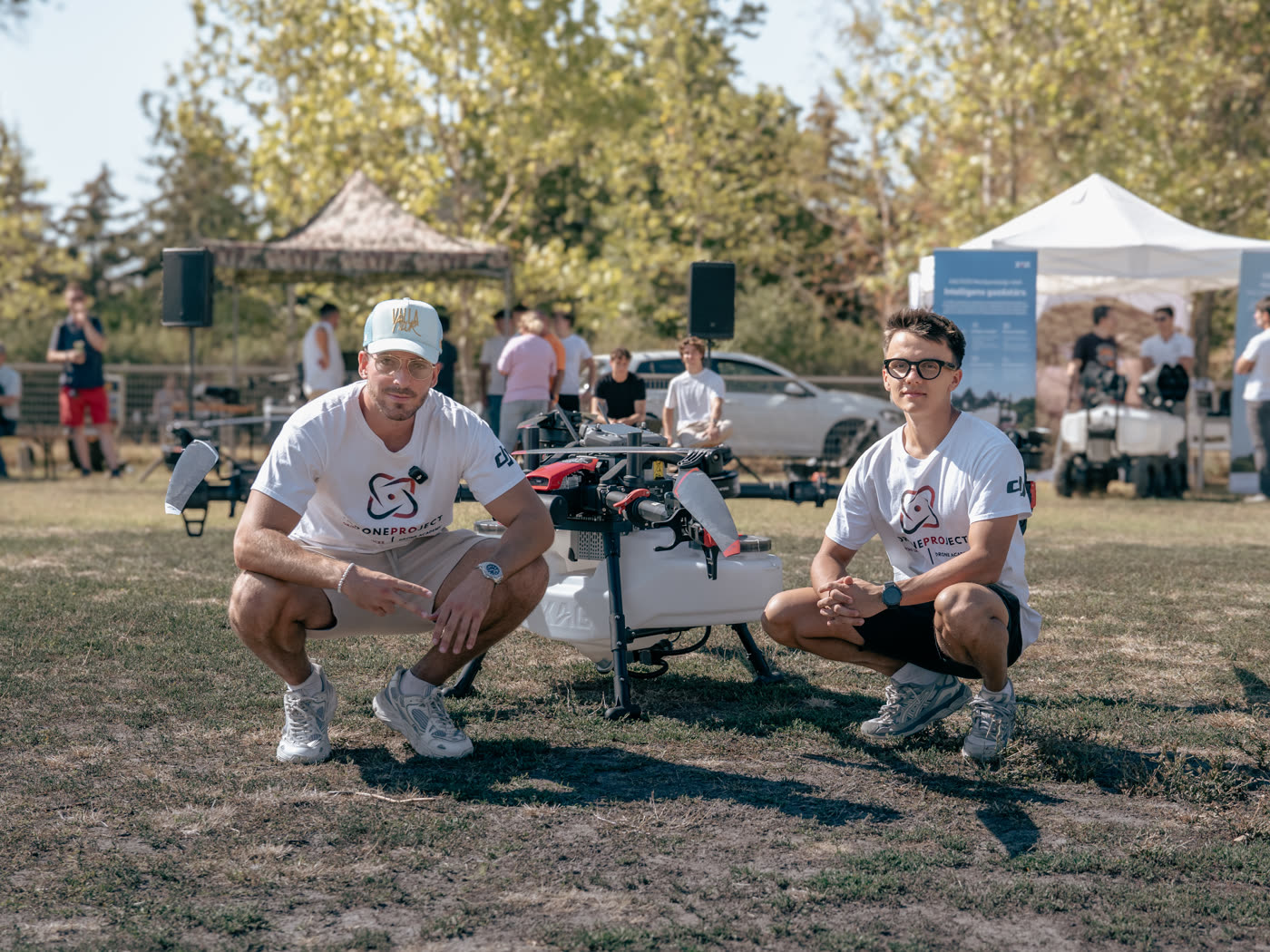 Az iDroneProject csapata egy nagy permetező drón mellett guggol a füvön